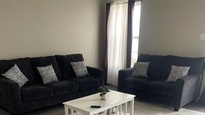 A living room with two dark sofas, a white coffee table, and a striped rug. - 3-bedroom townhome in tranquil Delmar with WiFi, AC. Relax and unwind (Delmar)