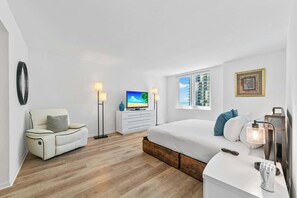 A modern bedroom with a bed, a sofa, a TV, and a desk.