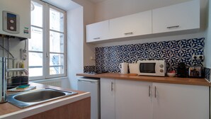 A modern kitchen with white cabinets, a wooden countertop, a built-in microwave, and a patterned backsplash. - Le Closmadeuc - Coeur de ville (Vannes)