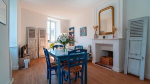 A dining area with a blue table and chairs, a fireplace, and a large mirror on the wall. - Le Closmadeuc - Coeur de ville (Vannes)