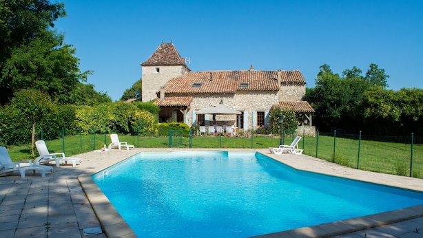 A swimming pool with lounge chairs, a stone building with a tiled roof, and a well-maintained lawn. - Le Four - Piscine Privée (Thénac)