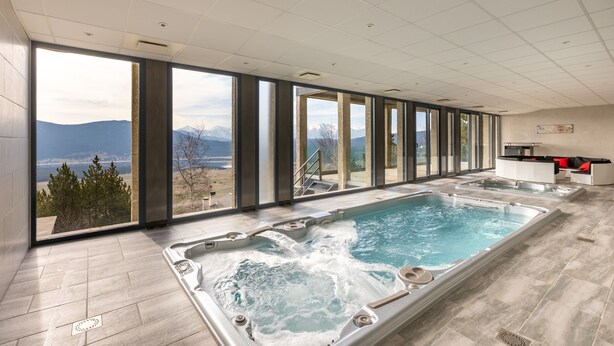 A large indoor swimming pool with a view of mountains and a lake.