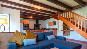 Una sala de estar con un sofá azul, una mesa de centro de madera y una escalera de madera.