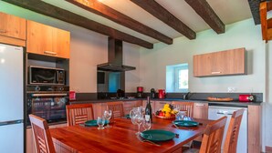 Una cocina moderna con armarios de madera, horno empotrado, microondas y un gran comedor preparado para seis personas.