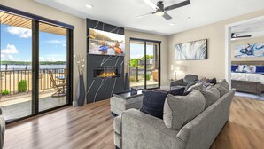 A modern living room with a fireplace, a sofa, and a view of a lake.