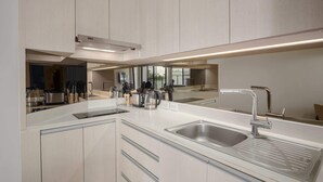 Une cuisine moderne dotée d’un grand miroir, d’appareils électroménagers en acier inoxydable et d’un plan de travail élégant.