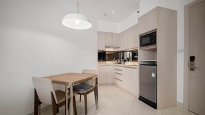 Une cuisine moderne équipée d’une table à manger, de chaises, d’un réfrigérateur et d’un four à micro-ondes.