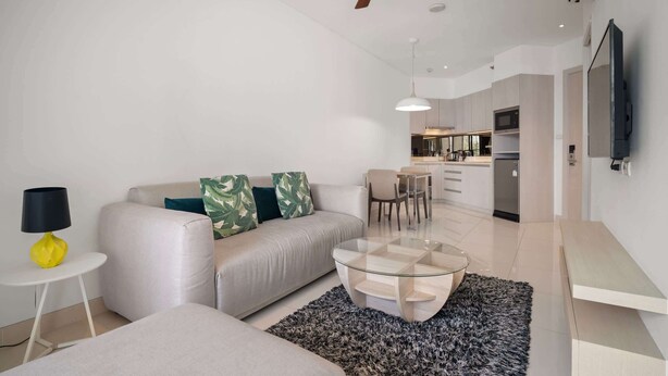 Una sala de estar moderna con sofá, mesa de centro y ventilador de techo.