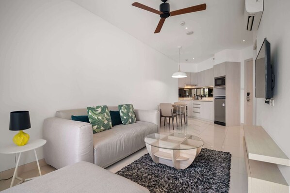 Una sala de estar moderna con sofá, mesa de centro y ventilador de techo.