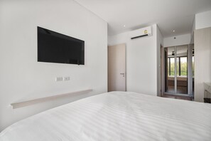 Une chambre moderne avec un grand lit, un téléviseur fixé au mur et un appareil de climatisation.
