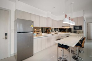 Una cucina moderna con frigorifero in acciaio inossidabile, un'isola grande con sgabelli da bar e illuminazione a sospensione.