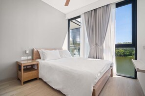 Un dormitorio moderno con una cama grande, una mesita de noche, una ventana con cortinas y vistas al exterior.