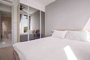 A modern hotel room with a large bed, a walk-in closet, and a bathroom with a shower and toilet.