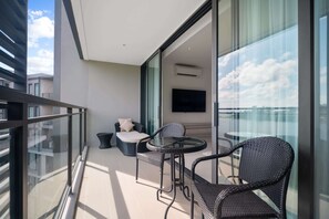 A balcony with a glass table and chairs, a sofa, and a TV. - Cassia Residences, Three-Bedroom B Premium Lake (Choeng Thale)