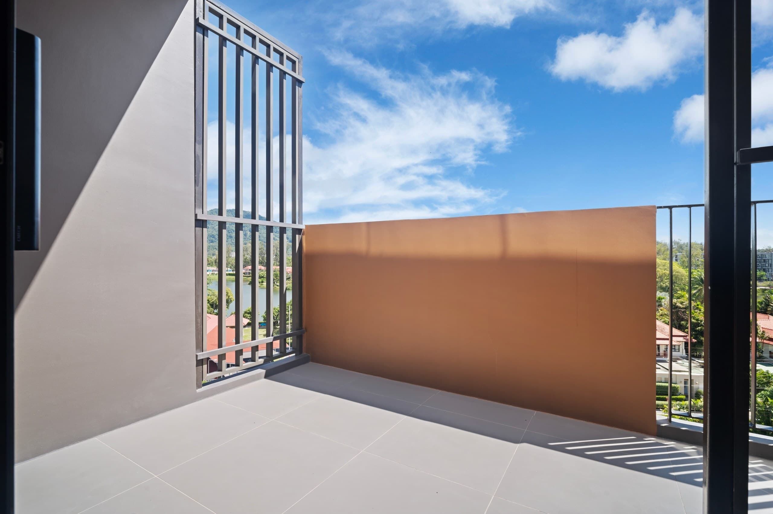 A balcony with a metal railing, a view of a body of water, and a clear sky.