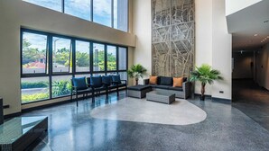 Eine großzügige Lobby mit großen Fenstern, hoher Decke und einer Wandverzierung.