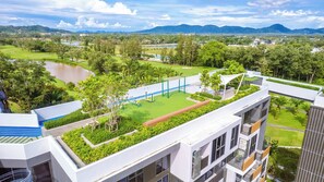 A rooftop garden with exercise equipment, a view of a lake, and surrounding greenery.