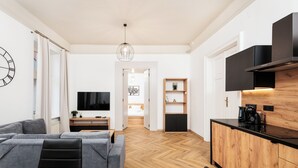 Una sala de estar moderna con un sofá, una mesa de comedor y una zona de cocina con encimera negra y armarios de madera.