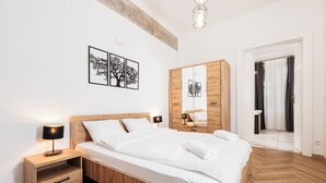 Un dormitorio moderno con una cama de madera, mesitas de noche, un armario y obras de arte en la pared.