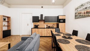 Una cocina moderna con armarios de madera, microondas integrado y un comedor con mesa de madera y sillas negras.