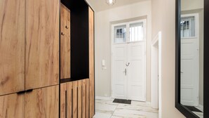 Un pasillo con un armario de madera, puertas dobles blancas y un espejo grande que refleja las puertas.