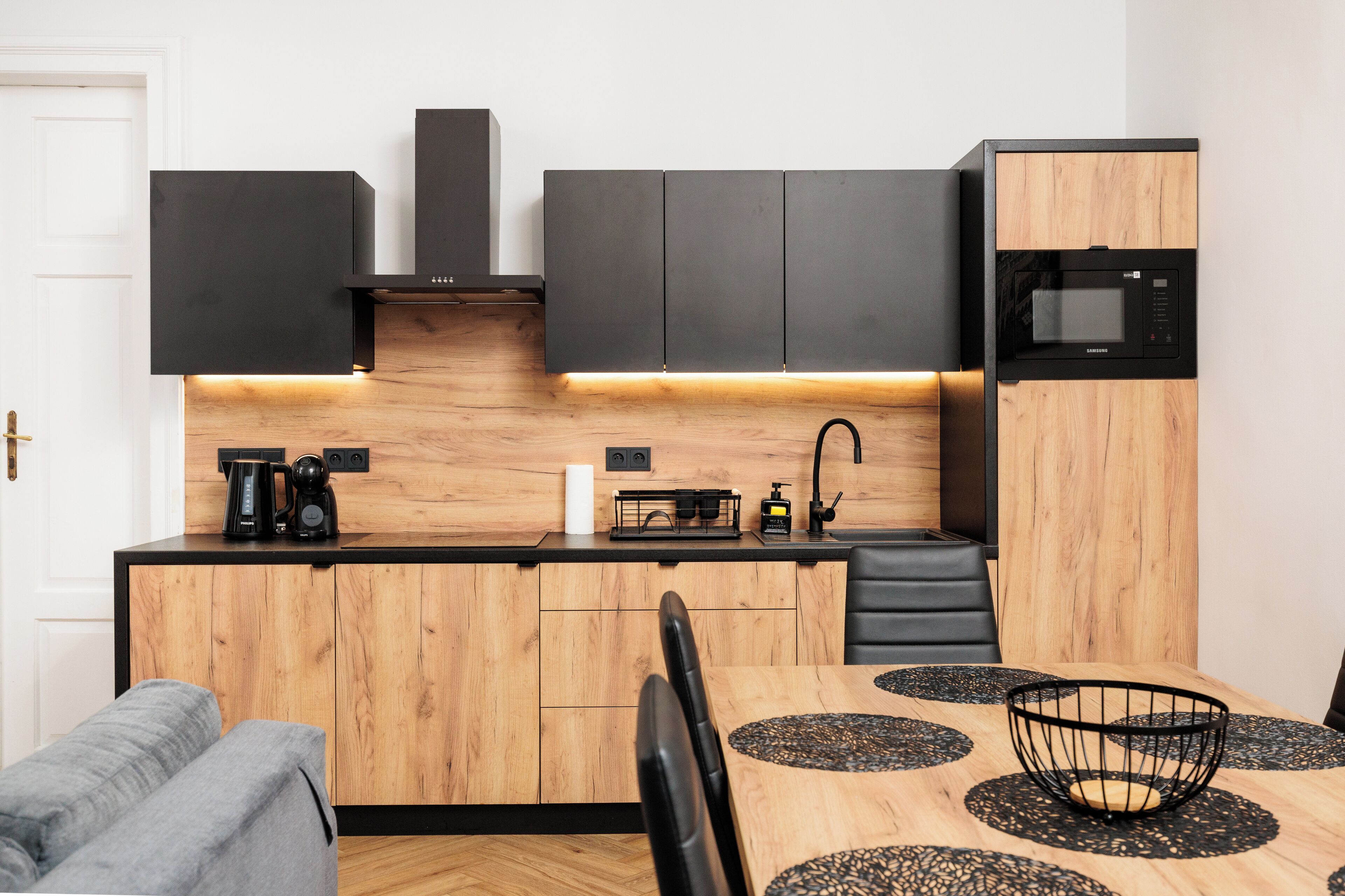 A compact kitchen with a wooden countertop, black cabinets, a microwave, and a coffee maker.