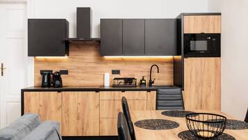 A compact kitchen with a wooden countertop, black cabinets, a microwave, and a coffee maker.