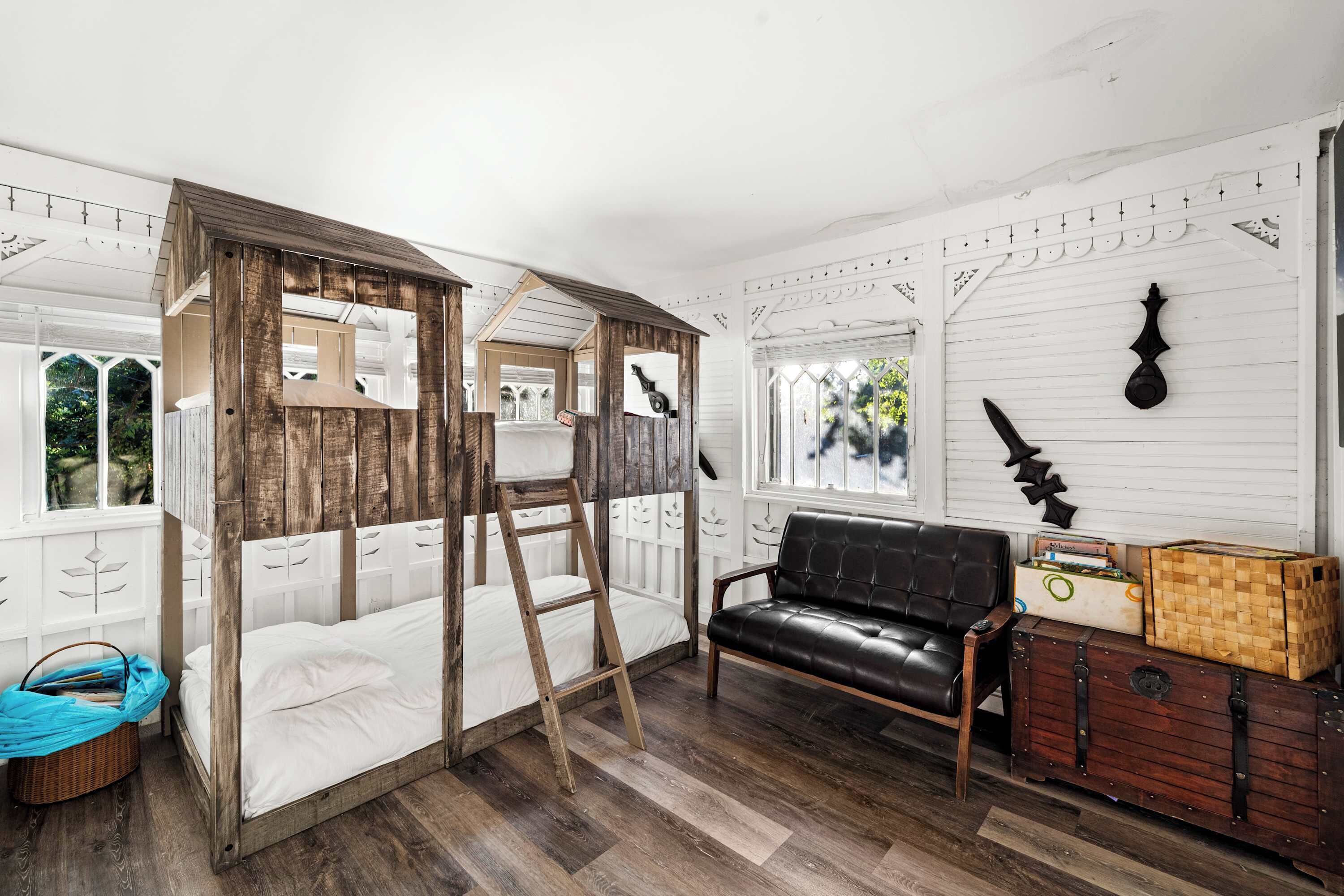 Una habitación con una cama de madera con dosel, un sofá de cuero negro y un aparador.