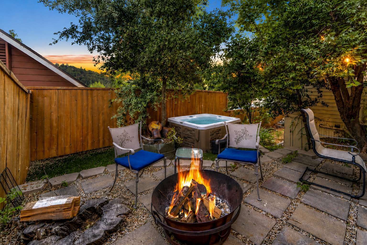 Un espace extérieur aménagé en patio, avec un foyer, deux chaises, une table et un jacuzzi.