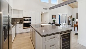 A modern kitchen with white cabinets, stainless steel appliances, and a large marble island. - Club Ironwood Resort Access, Desert Garden & Golf (Carefree)