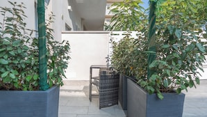 Un espacio al aire libre moderno con plantas en macetas y una silla de mimbre.