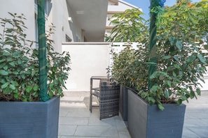 Un espacio al aire libre moderno con plantas en macetas y una silla de mimbre.