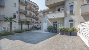 Un patio con suelo empedrado, rodeado de edificios con balcones y macetas.