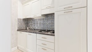 A kitchen with white cabinets, a patterned backsplash, and a gas stove.