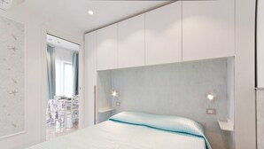 A bedroom with a bed, a headboard, bedside tables, and a door leading to a bathroom.