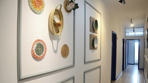 A hallway with framed wall art, a ceiling fan, and a door leading to another room. - Metro Hotel (Aguas de Lindoia)