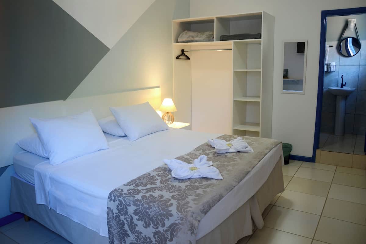 Ein Hotelzimmer mit Bett, Kleiderschrank, Spiegel und Badezimmer.