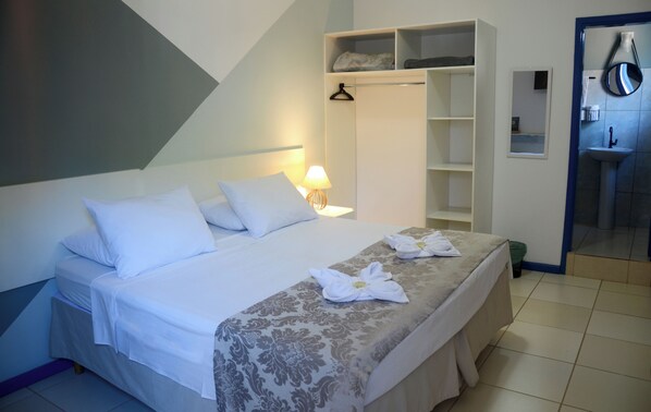A hotel room with a bed, a wardrobe, a mirror, and a bathroom.