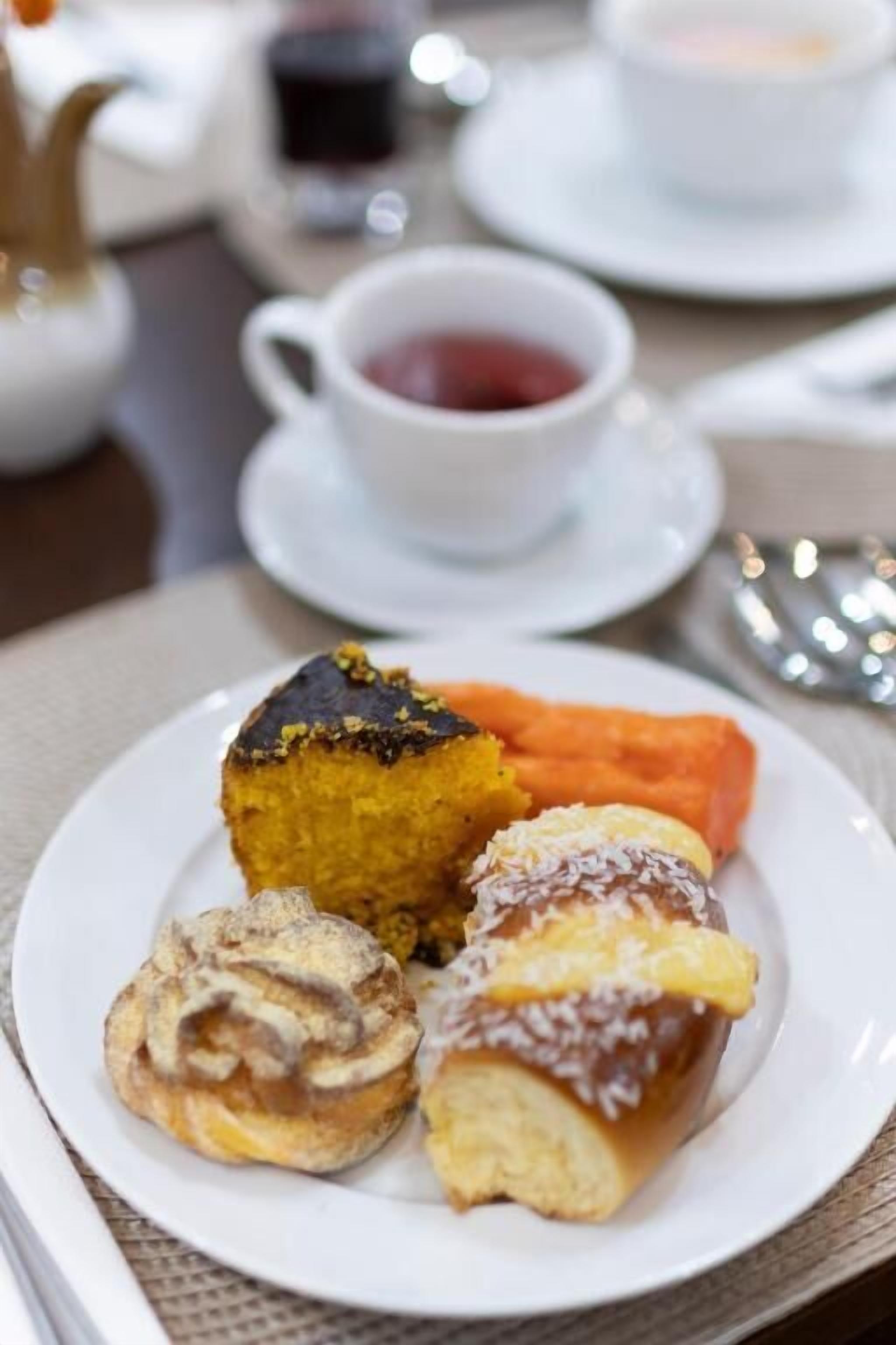 A plate with pastries and a cup of tea on a table.