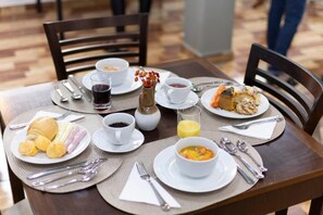A breakfast table set with plates of food, cups, and cutlery. - Metro Hotel (Aguas de Lindoia)
