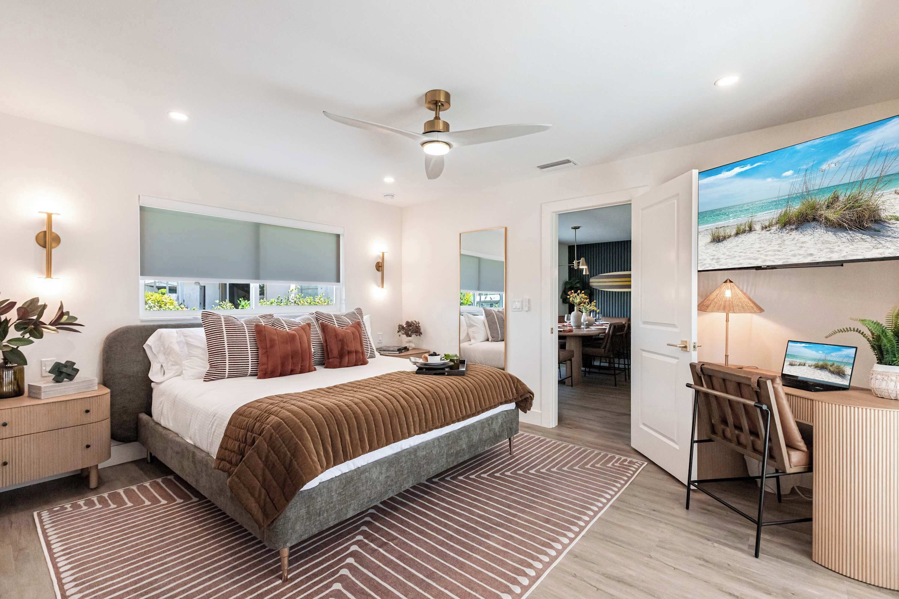 A modern bedroom with a large bed, a desk, and a TV.