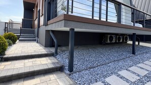 Un bâtiment moderne doté d’un toit en pente, de grandes fenêtres et d’un chemin pavé menant à un escalier.
