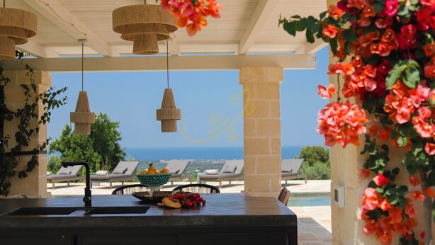 A covered outdoor area with a view of the sea, a table with fruits and a bowl, and hanging light fixtures. - TD ApulianRetreat Scenic Villa with hammam & pool (Costa Merlata)