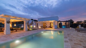 A modern outdoor pool area with a pergola, seating, and a glass-enclosed structure. - TD ApulianRetreat Scenic Villa with hammam & pool (Costa Merlata)
