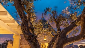 A stone building with a large tree in the foreground, a small window, and a stone wall. - TD ApulianRetreat Sea view trullo w/heated pool (Costa Merlata)