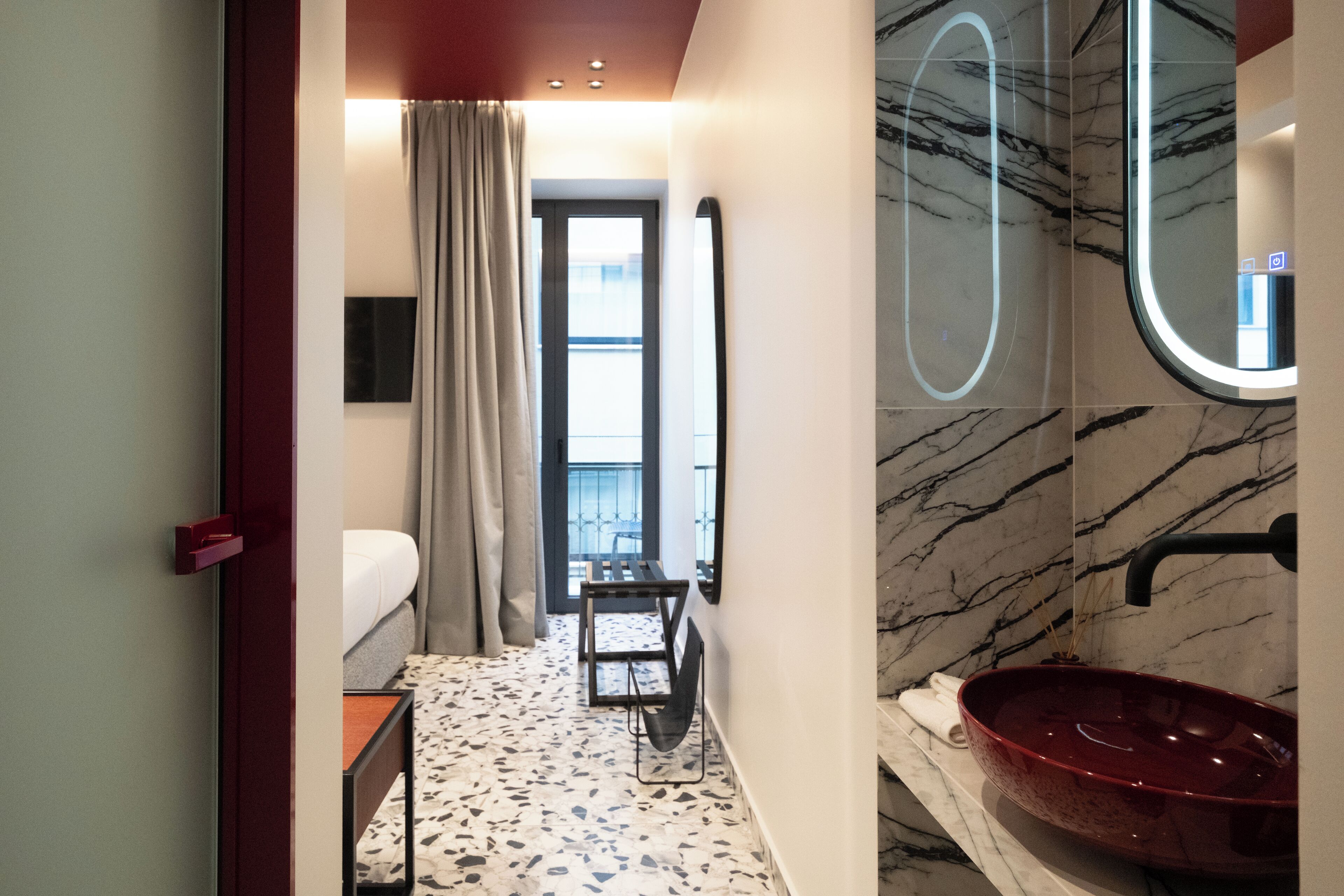 A hotel bathroom with a marble sink, a mirror, a towel, and a view of the outdoors.