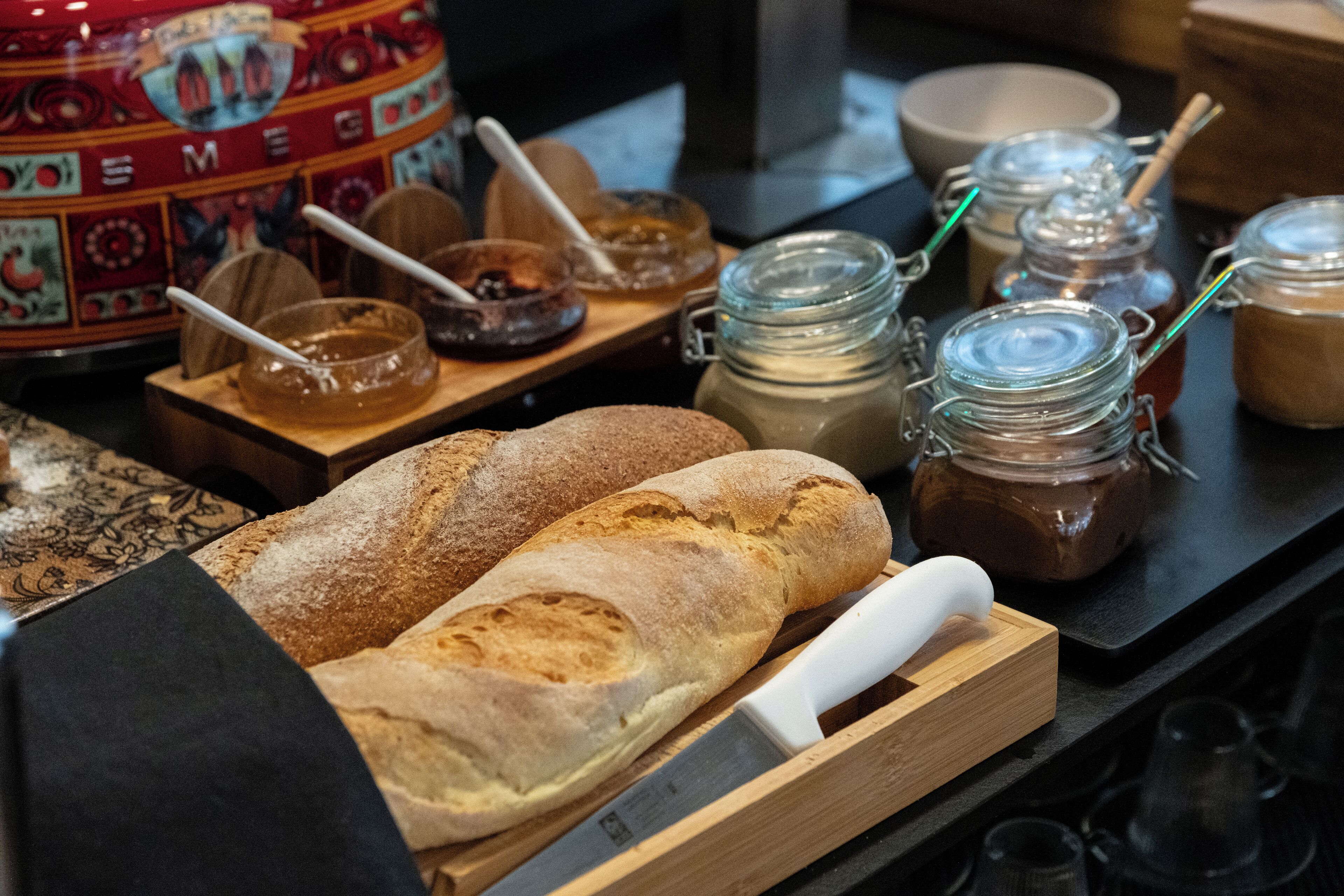 Exposição de pão e potes de pastas numa mesa de madeira.