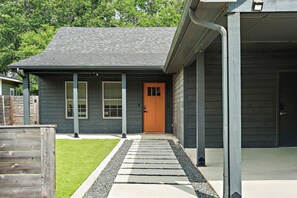 A modern house with a dark exterior, a wooden front door, and a covered porch area.