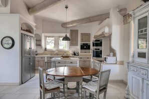 A kitchen with a wooden table, white cabinets, and a stainless steel refrigerator.