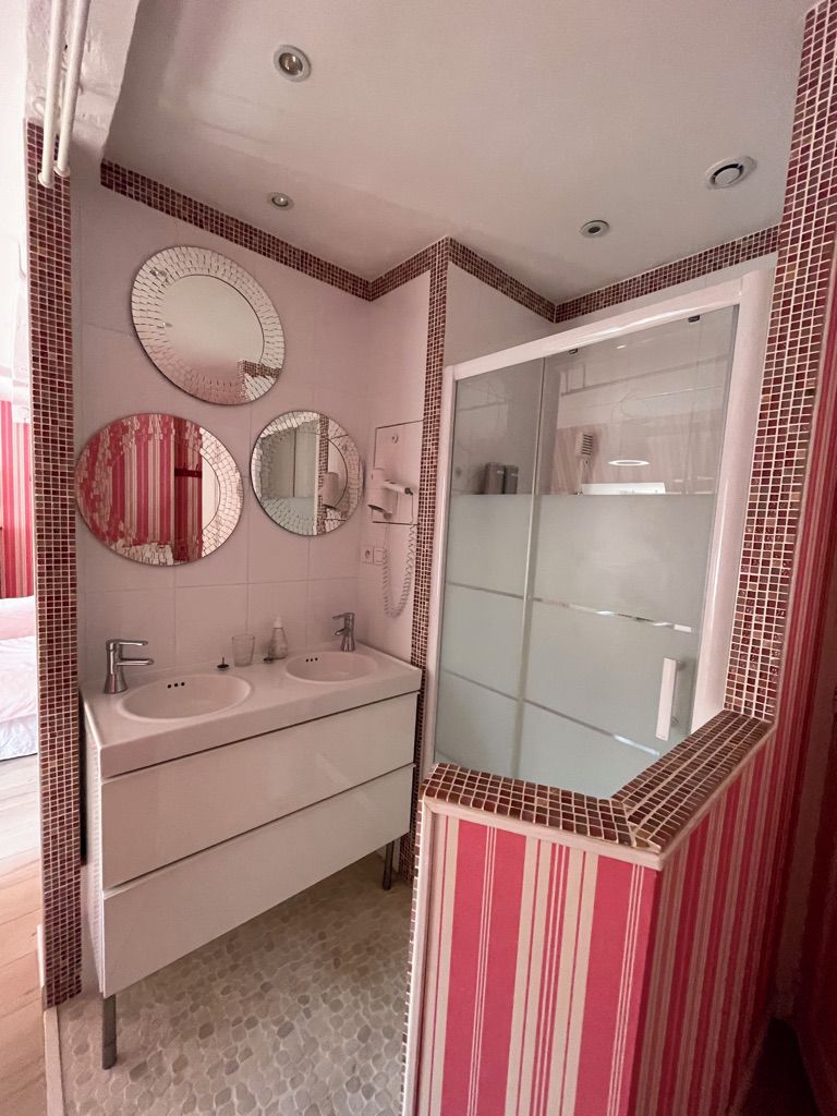 Un baño con dos lavamanos, un espejo y cabina de ducha de vidrio.